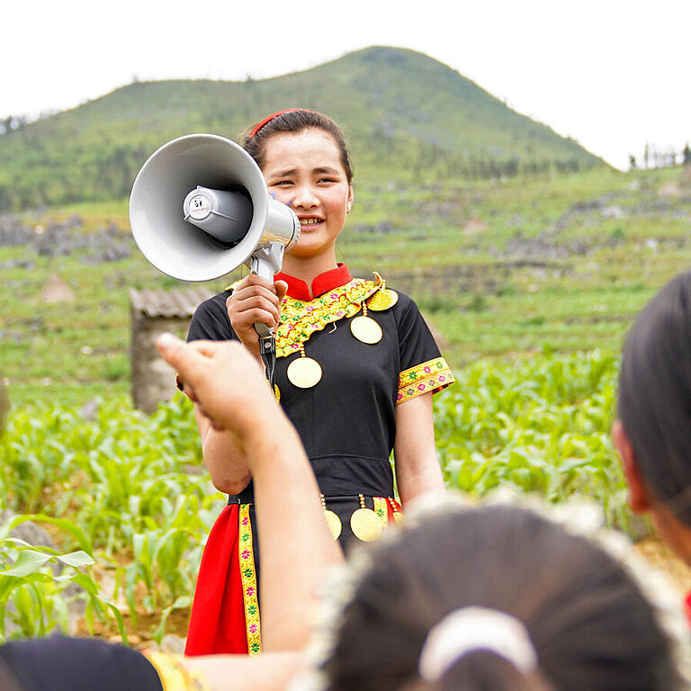 Ein Mädchen steht vor einer Gruppe Kinder und spricht in ein Megaphon.