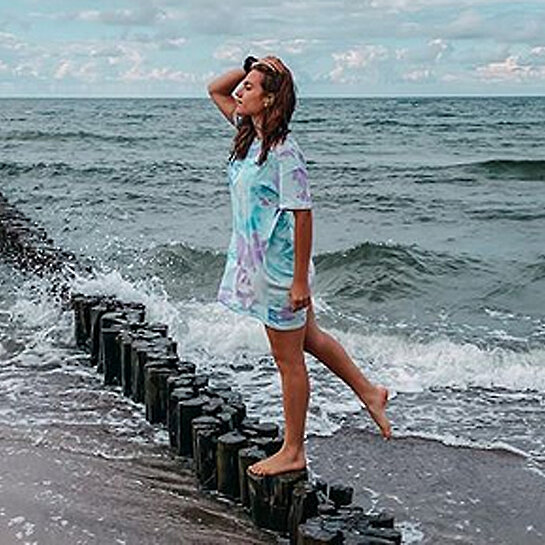 Luisa steht auf Holzpfahl im Meer.