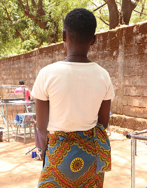 Aline steht in ihrer Gemeinde in Burkina Faso
