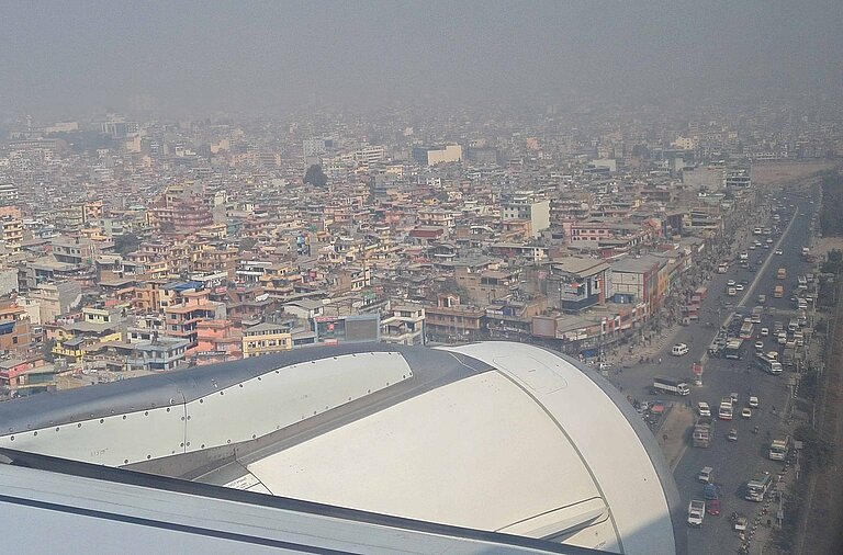 Ein Flugzeug setzt zur Landung über den Dächern der nepalesischen Hauptstadt Kathmandu an.