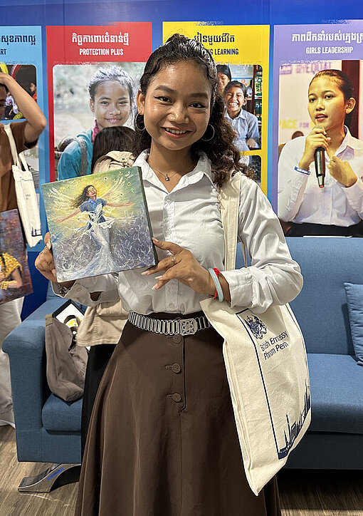 Eine kambodschanische junge Frau hält ein kleines Gemälde in der Hand