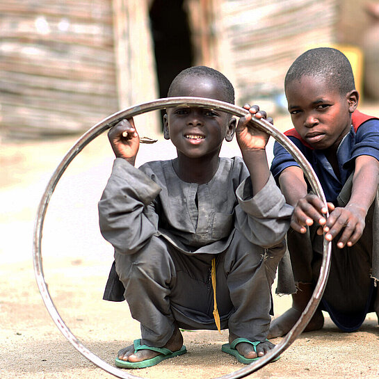 jungen-in-nigeria-spielen-mit-reifenfelge