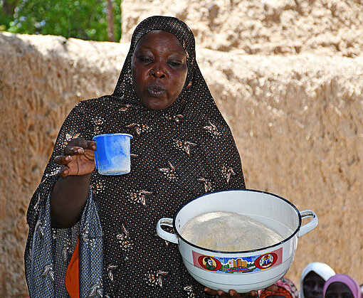 Eine Frau hält einen Topf mit Mehl und einen Messbecher in der Hand