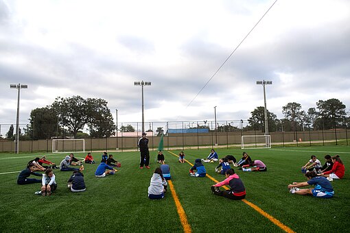 Die gesamte Mädchenfußballmannschaft macht sich warm, dehnt sich auf dem Spielfeld