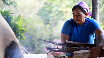 Bäckerin in Honduras legt Feuerholz für Lehmofen nach