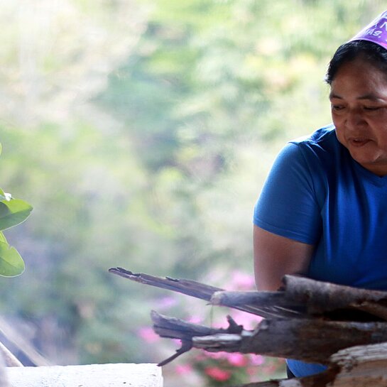 Bäckerin in Honduras legt Feuerholz für Lehmofen nach