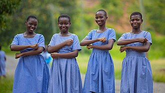 Schülerinnen in blauen Schuluniformen lächeln gemeinsam im Freien