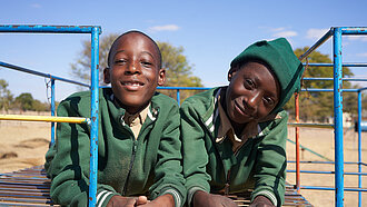 Zwei elfjährige Jungen aus Simbabwe sitzen auf einem Klettergerüst