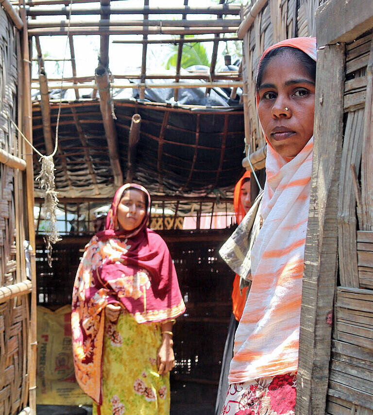 Zwei Frauen stehen in ihrem zerstörten Haus in Bangladesch