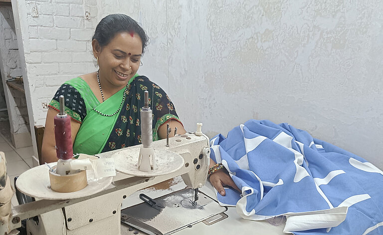 Eine Mitarbeiterin von Rami Prints sitzt an einer Nähmaschine und arbeitet an dem Baumwolltuch.