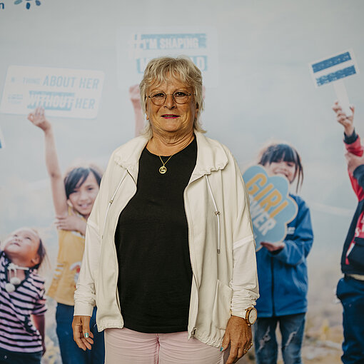 Dr. Heike Solbrig-Lebuhn, Stifterin des Monats bei der Stiftung Hilfe mit Plan, vor einem Hintergrund mit Kindern und Empowerment-Slogans.