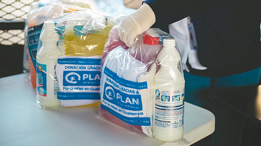 Zwei gepackte Hygienekits stehen auf einem Tisch. Sie enthalten unter anderem ein Handtuch und Seife.