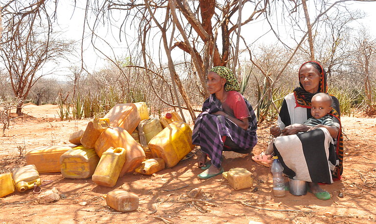 Zwei Äthiopische Frauen warten mit Kanistern auf Trinkwasser