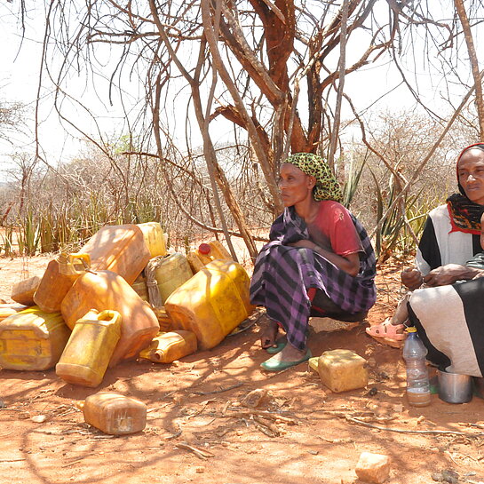Zwei Äthiopische Frauen warten mit Kanistern auf Trinkwasser