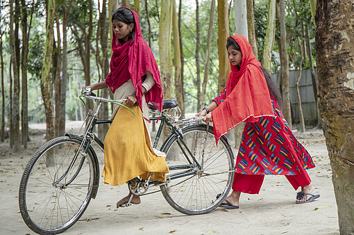Zwei junge Mädchen mit Fahrrad unterwegs