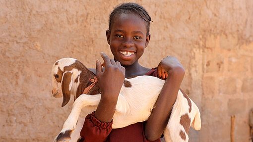 Ziegen für eine Ziegenzucht in Malawi Ainee hält eine Baby-Ziege auf dem Arm.