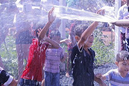 Kinder spielen an dem neuen Brunnen in ihrer Gemeinde Kinder spielen an dem neuen Brunnen in ihrer Gemeinde
