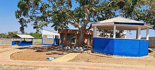 Schutzhaus mit blau-weiß gestrichenen Pavillons und großem Baum im Garten, gebaut im Rahmen unseres Projekts in Äthiopien