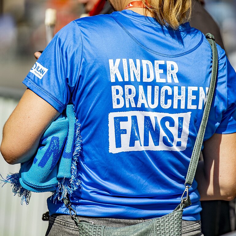 Eine Frau trägt ein T-Shirt der Kampagne "Kinder brauchen Fans!"