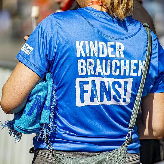 Eine Frau trägt ein T-Shirt der Kampagne "Kinder brauchen Fans!"