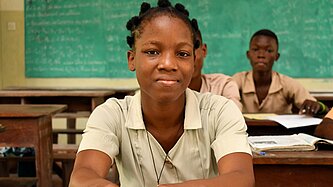 Monique sitzt an ihrem Platz im Klassenzimmer und folgt dem Unterricht