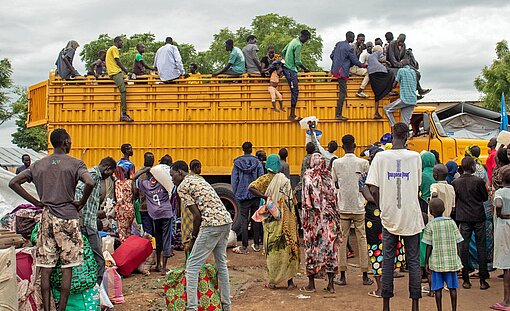 Ein gelber lastwagen bringt Flüchtlinge