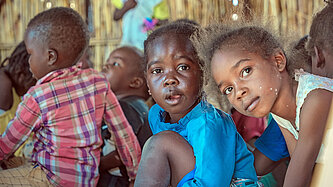 Zwei Kinder schauen aus einer Notunterkunft