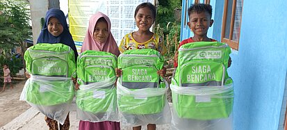Kinder halten geschenkte Rucksäcke in den Händen