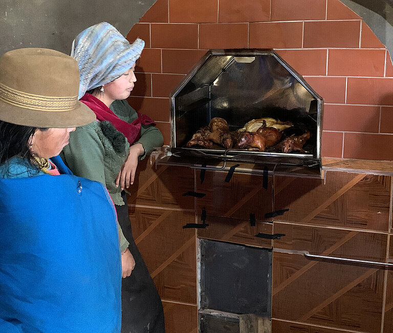 Zwei Frauen kochen Meerschweinchen im ökologischen Ofen