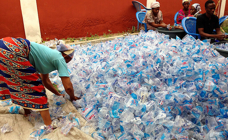 Eine Frau sortiert einen riesigen Berg an gewaschenen Plastikbeuteln.