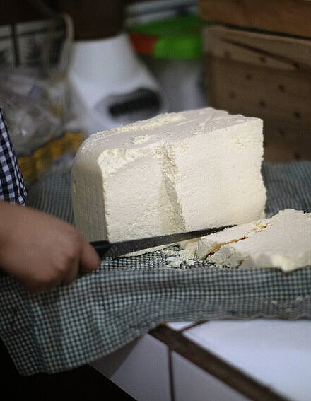 Ein Quarkblock liegt auf einem Tuch und ist bereit zur Reifung zu Käse