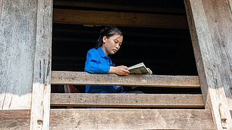 Ein vietnamesisches Mädchen sitzt am Fenster und liest ein Buch