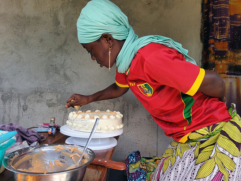 Eine junge Frau dekoriert eine Torte mit Glasur