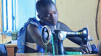 Natabo, 13, lernt in einem beruflichen Training in Kapoeta wie Kleidung geschneidert wird © Plan