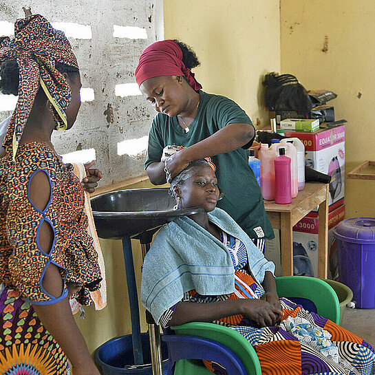 Ein Frau frisiert die Haare einer Kundin