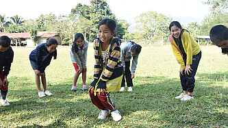Khai steht mit anderen Mädchen auf einem Sportplatz.