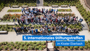 Eine große Gruppe von Menschen versammelt sich im Garten des Klosters Eberbach während des 5. Internationalen Stiftungstreffens der Stiftung Hilfe mit Plan.