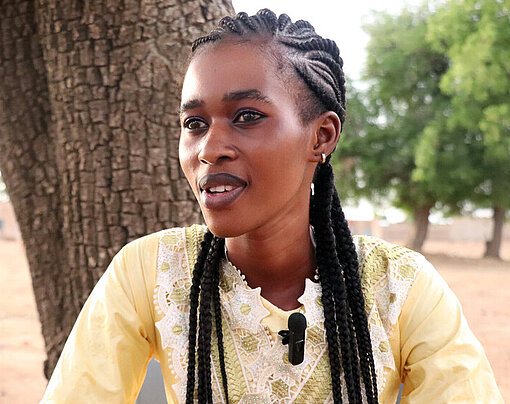 Elisabeth sitzt draußen in ihrer Gemeinde in Nakambé