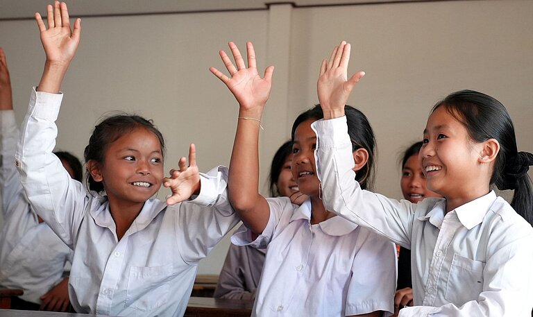 Drei Mädchen sitzen fröhlich im modernen Klassenzimmer einer Schule in Laos