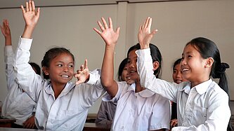 Drei Mädchen sitzen fröhlich im modernen Klassenzimmer einer Schule in Laos