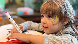 Ein junges Mädchen sitzt an einem Tisch und malt