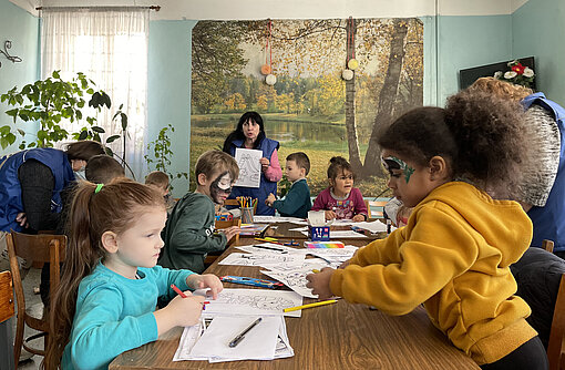 Mehrere Kinder sitzen an einem Tisch und malen