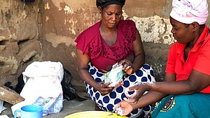 Zwei Frauen kneten Teig in einer Schüssel und bereiten Brot in Malawi zu