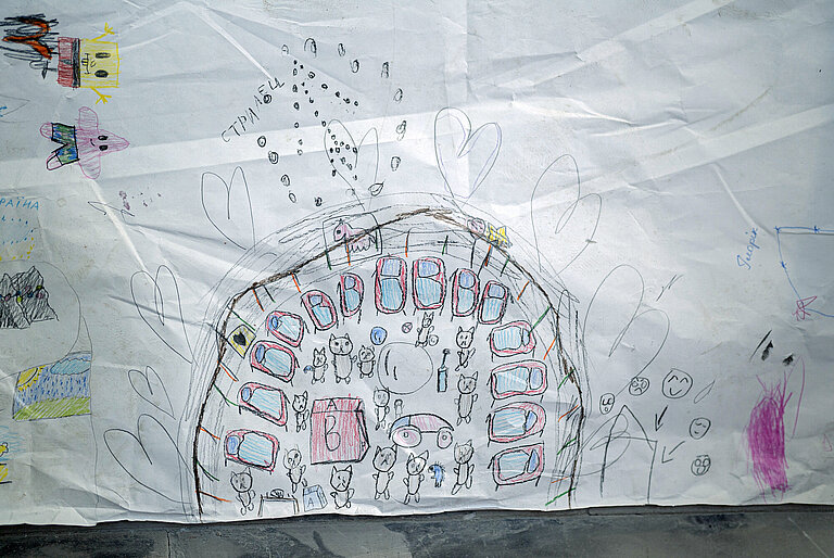 Ein von Kindern gemaltes Bild. Darauf zu sehen sind ein Halbkreis aus Betten um zahlreiche Katzen herum. Daneben sind große Herzen gezeichnet.