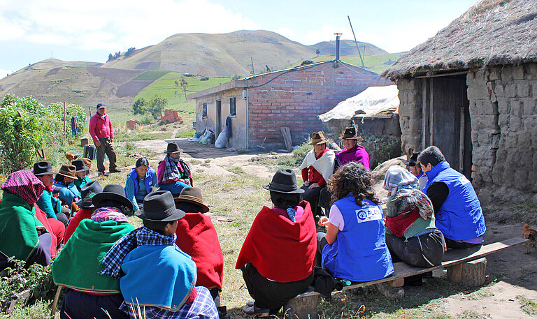 Gruppe indigener Ecuadorianer:innen im Halbkreis sitzend
