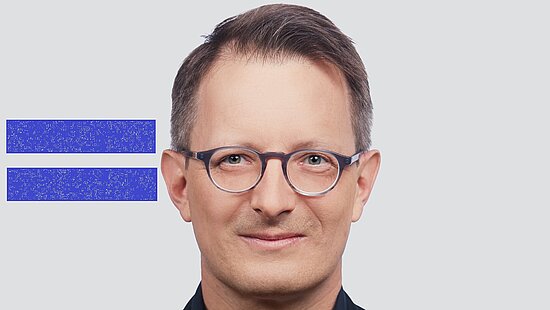 Alexander King neben dem blauen Girls Get Equal-Gleichzeichen.