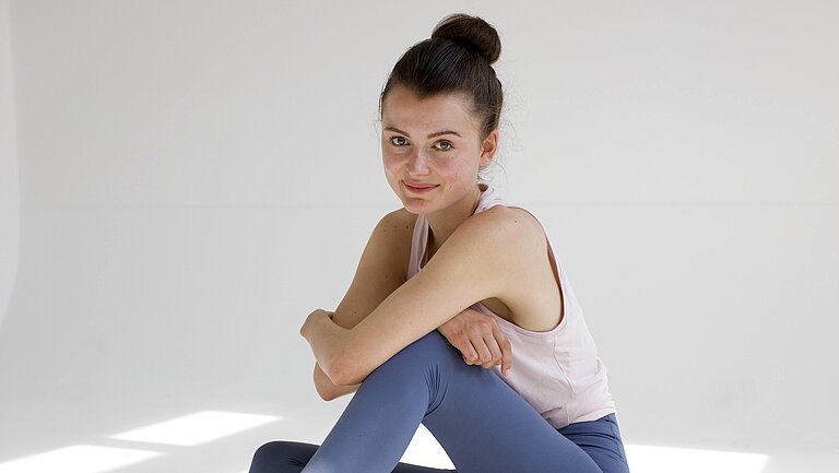 Hannah sitzt auf dem Boden vor weißem Hintergrund.