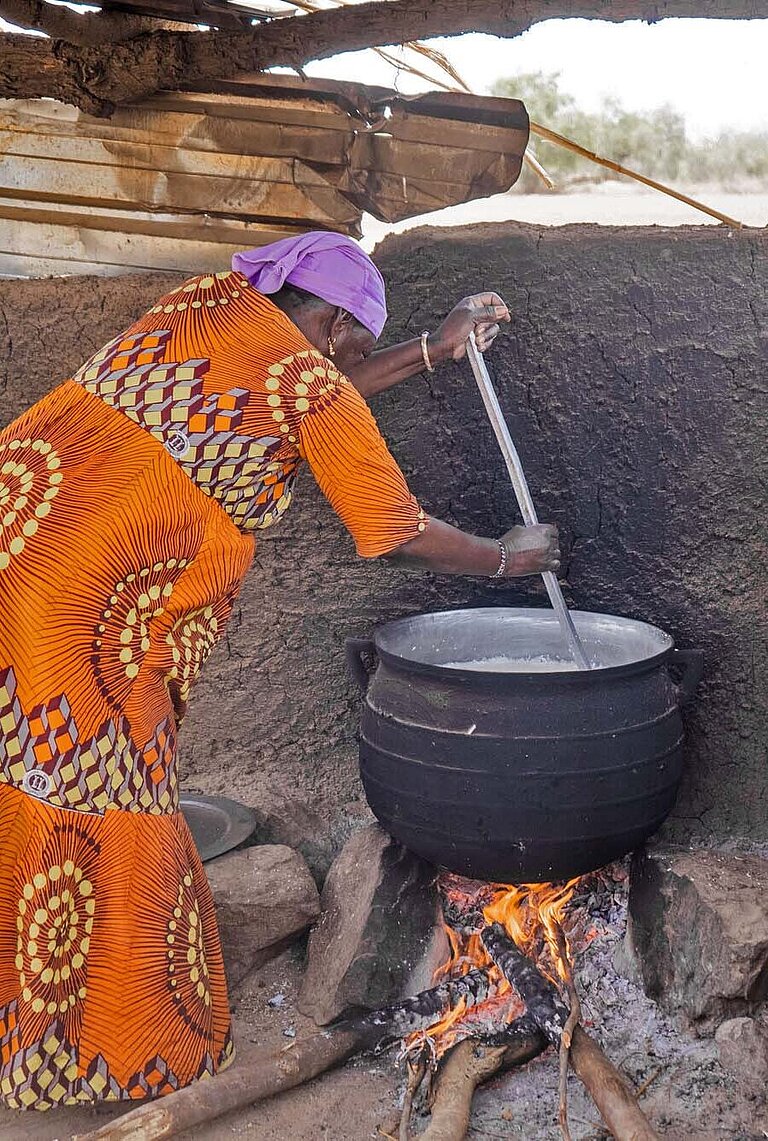 Eine Frau in einem bunten Kleid kocht
