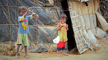 Zwei Kinder spielen vor einer Hütte im Flüchtlingscamp von Cox's Bazar. ©Plan International/Jane Gardner