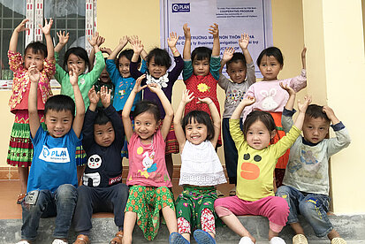 Immobilien spenden für bessere Zukunftsperspektven von Kindern Gruppe lachender Kinder vor einem von Plan International unterstützten Schulgebäude in Vietnam